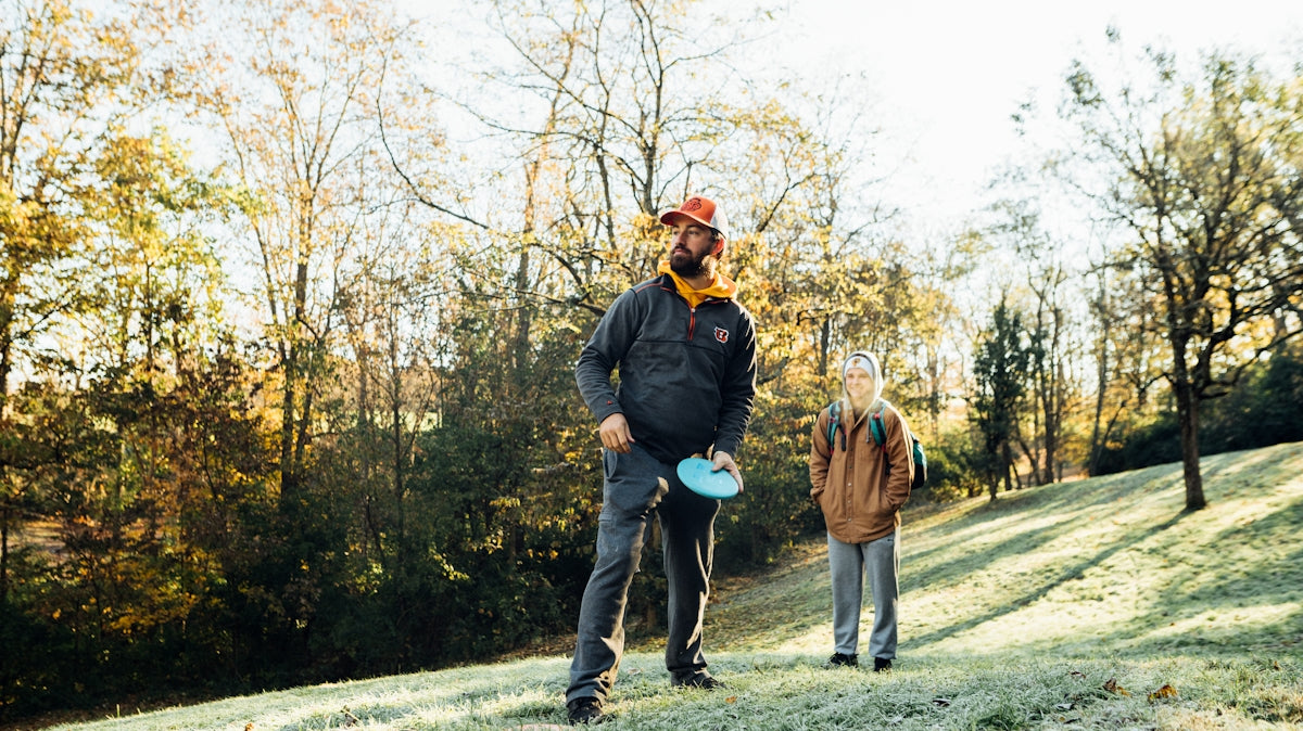 a man holding a frisbee while standing next to another man