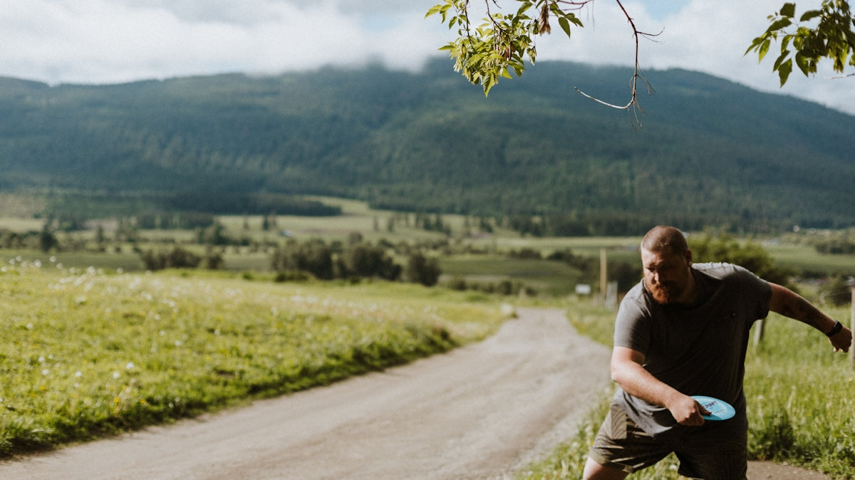 a man holding a frisbee on a dirt road