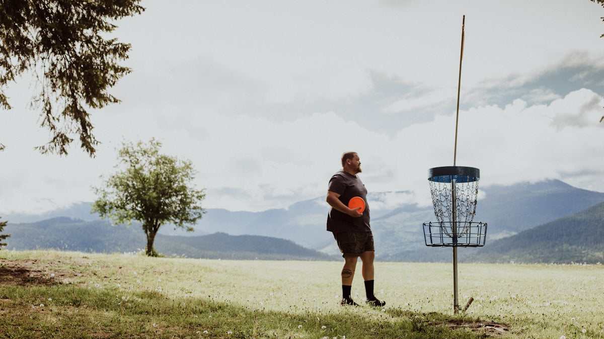a man holding a frisbee standing in a field