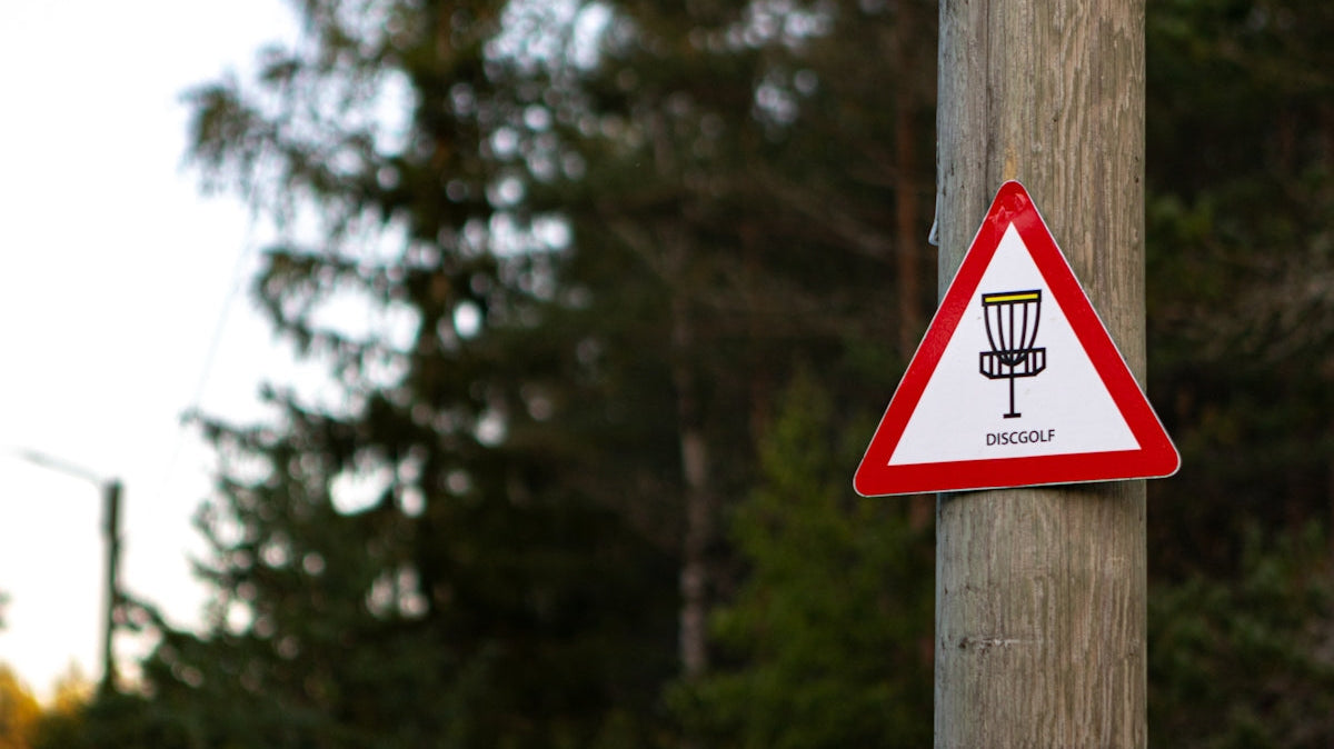 a red and white sign on a wooden pole