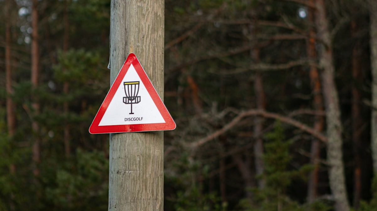 a red and white sign on a wooden pole