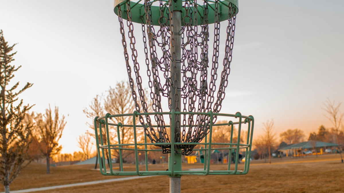 a green frisbee golf basket in a field