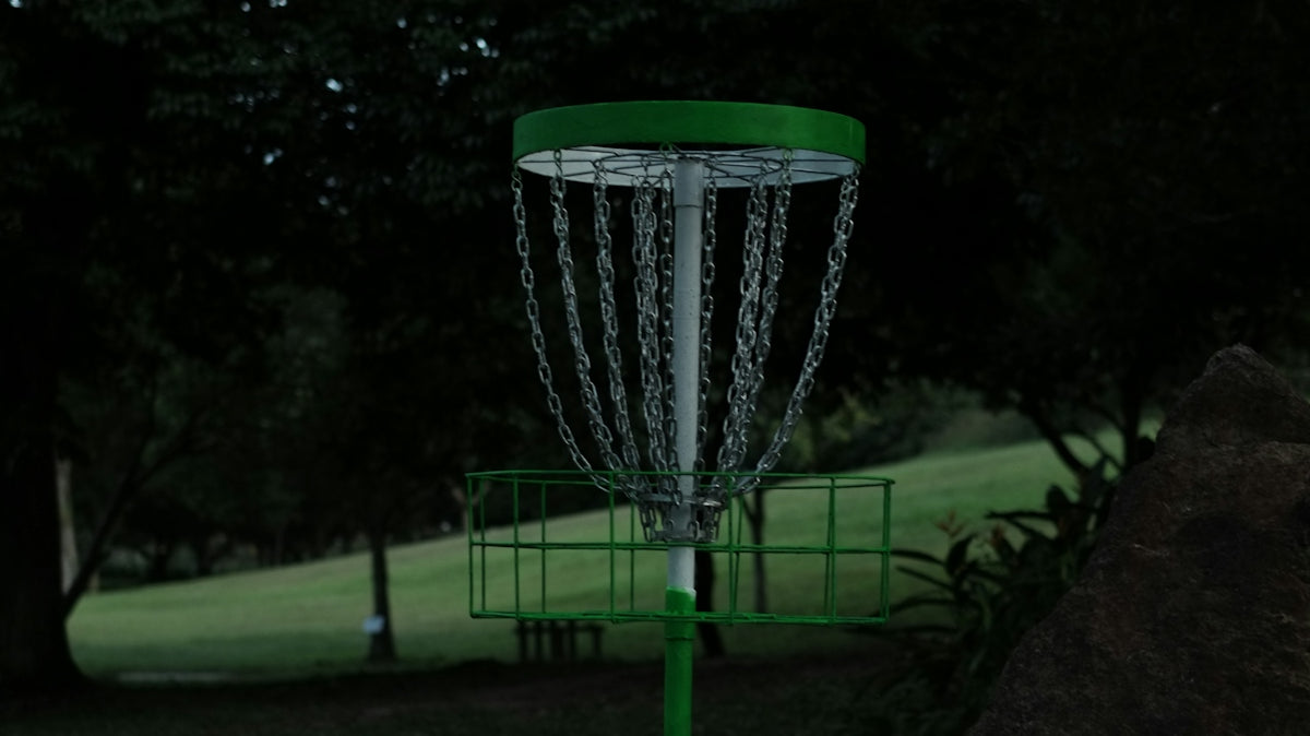 a green and white frisbee is in the air