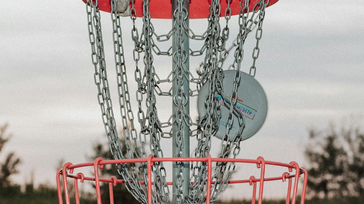 A frisbee golf basket with chains attached to it