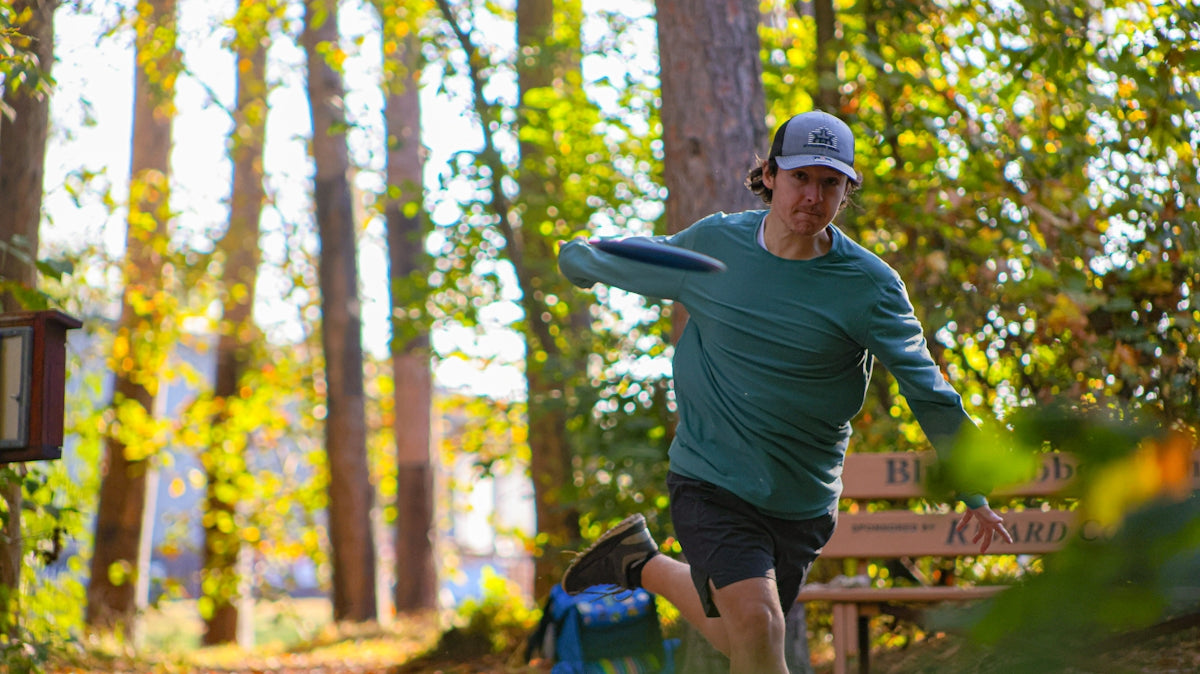 A man in a green shirt is throwing a frisbee