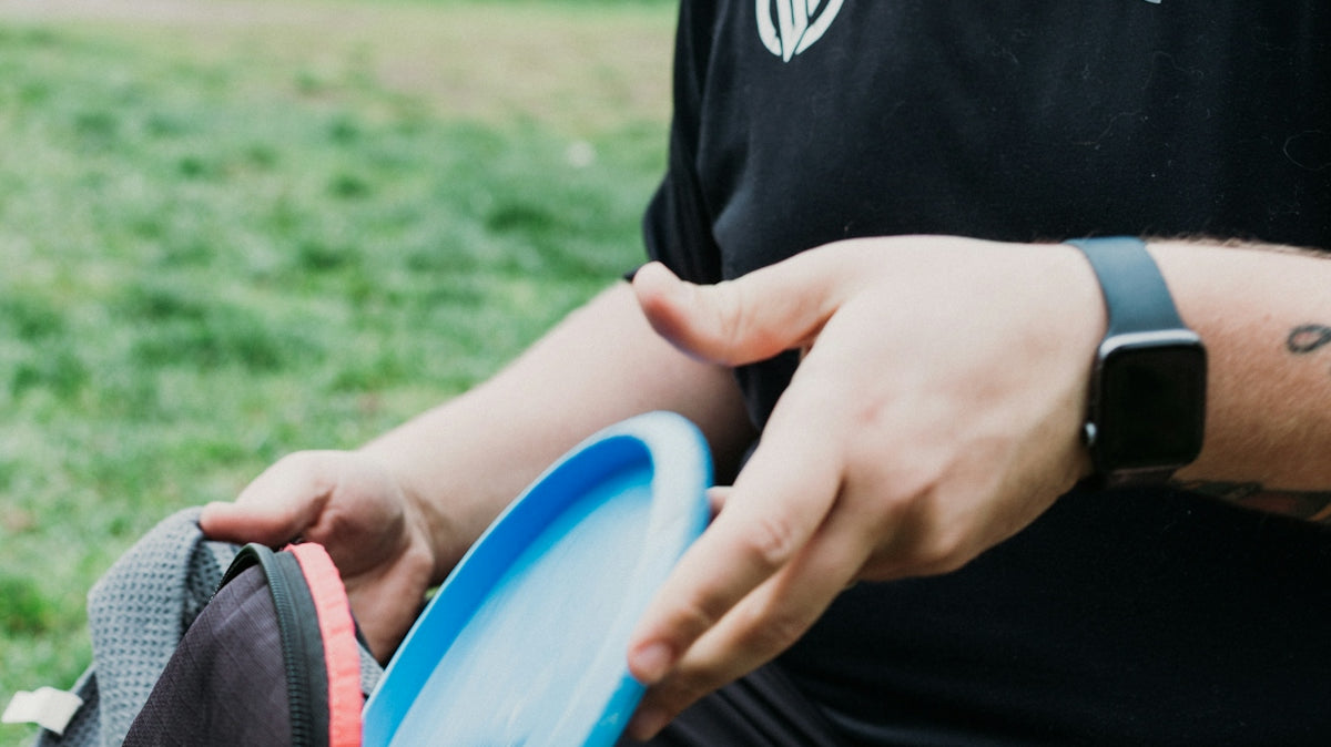 Man placing a disc golf disc into a bag