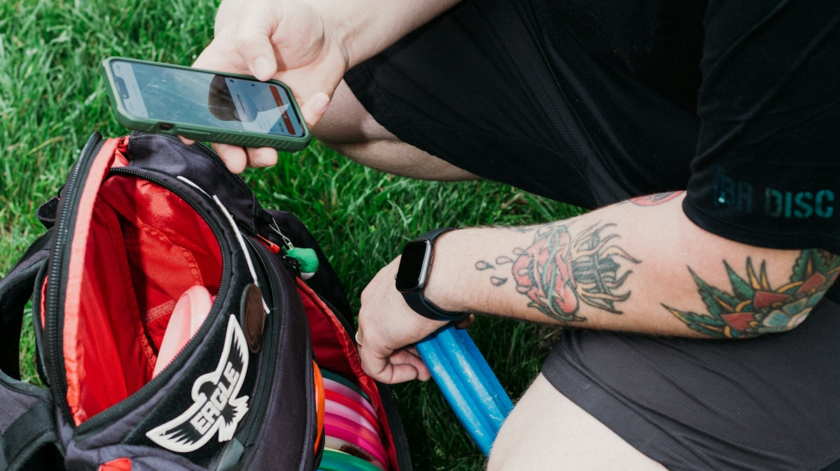 Man packing disc golf bag with phone and water bottle