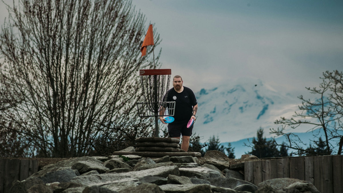 Man playing disc golf with mountains in background