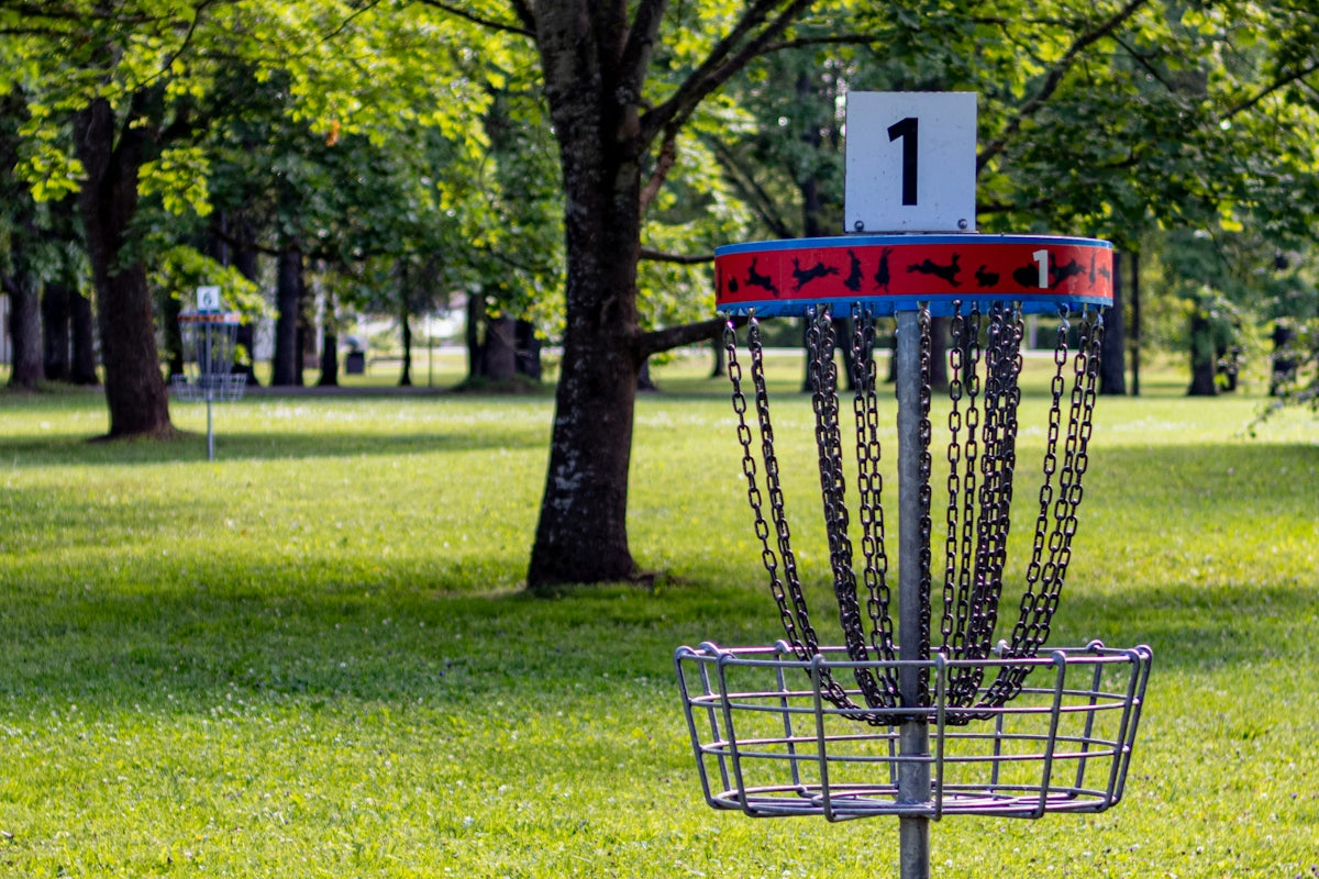 a frisbee golf cage in a park with trees