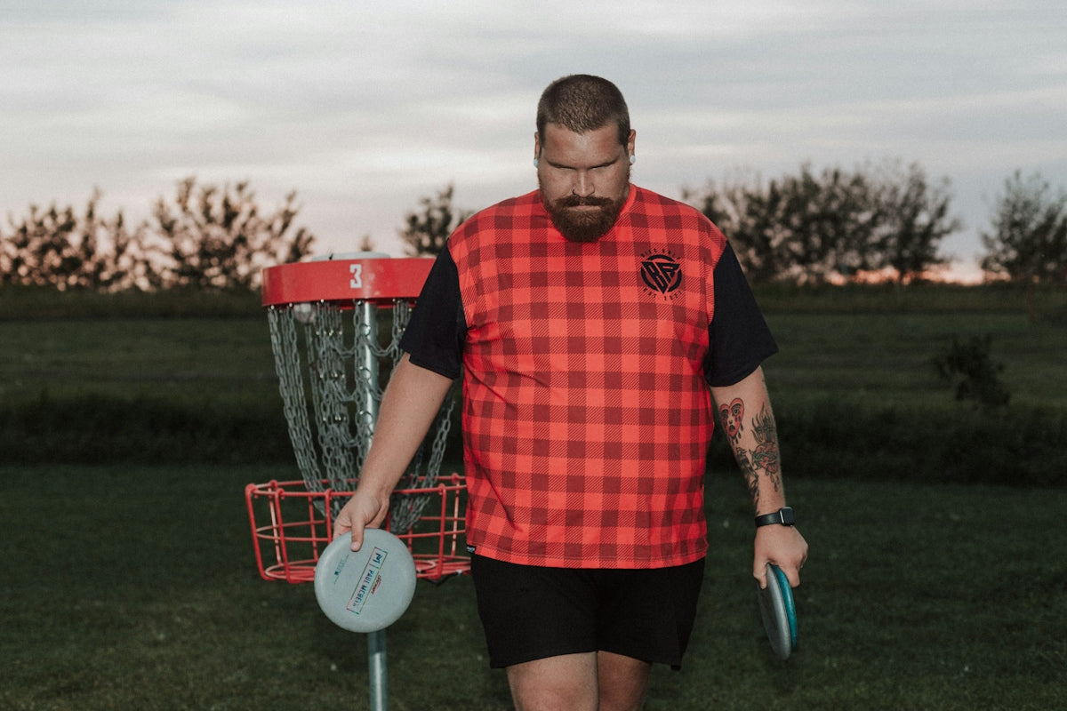 A man holding a frisbee standing next to a frisbee golf net