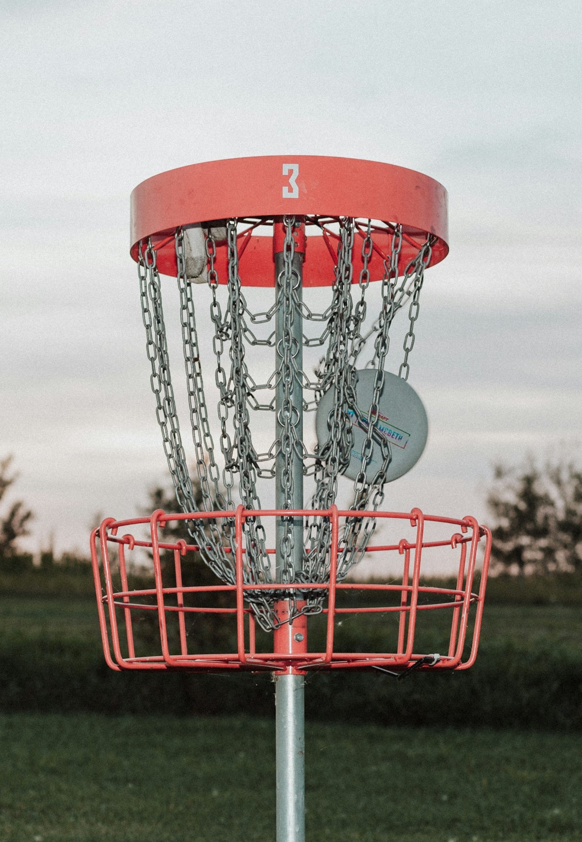 A frisbee golf basket with chains attached to it