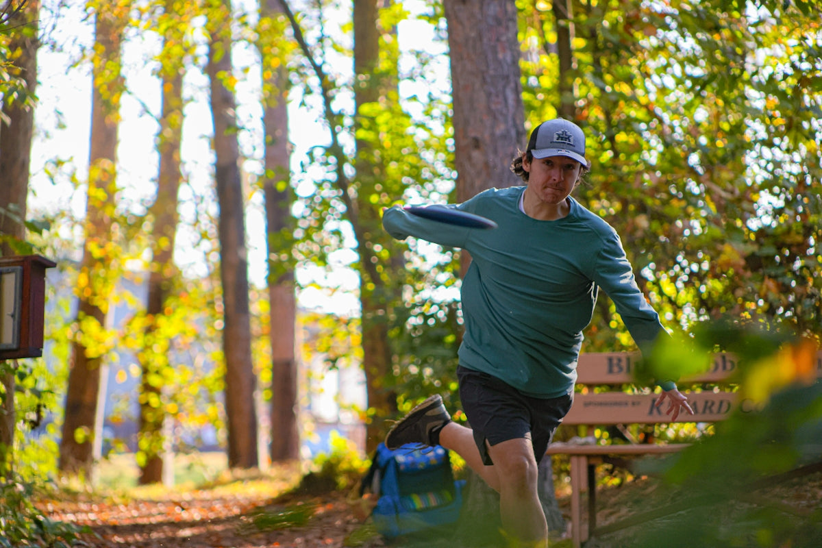 A man in a green shirt is throwing a frisbee
