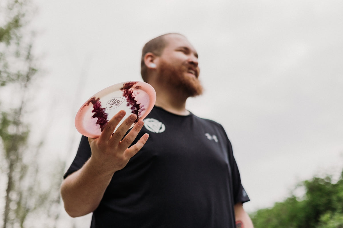 Man holding a disc golf disc outdoors