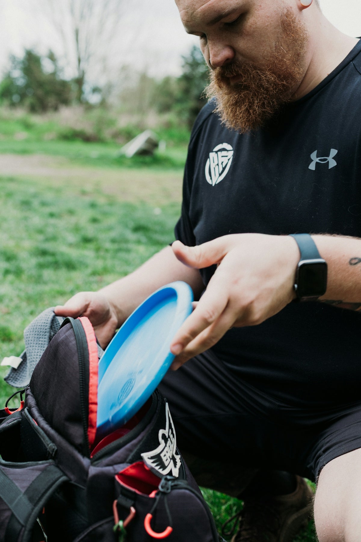 Man placing a disc golf disc into a bag
