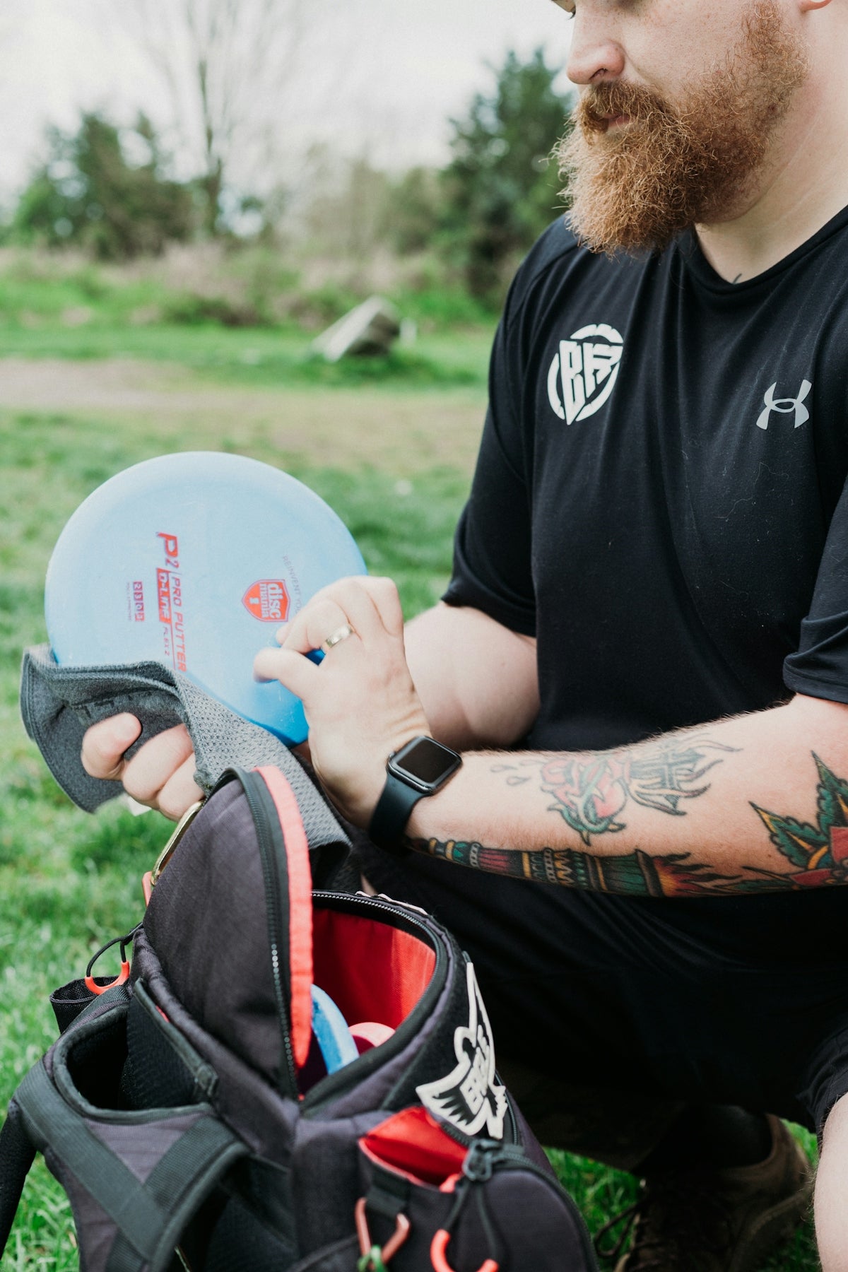 Man with beard and tattoos holding a disc golf disc