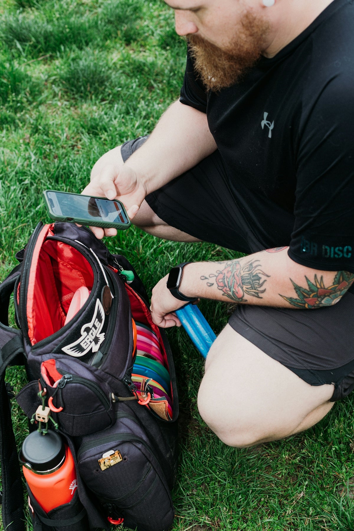 Man packing disc golf bag with phone and water bottle