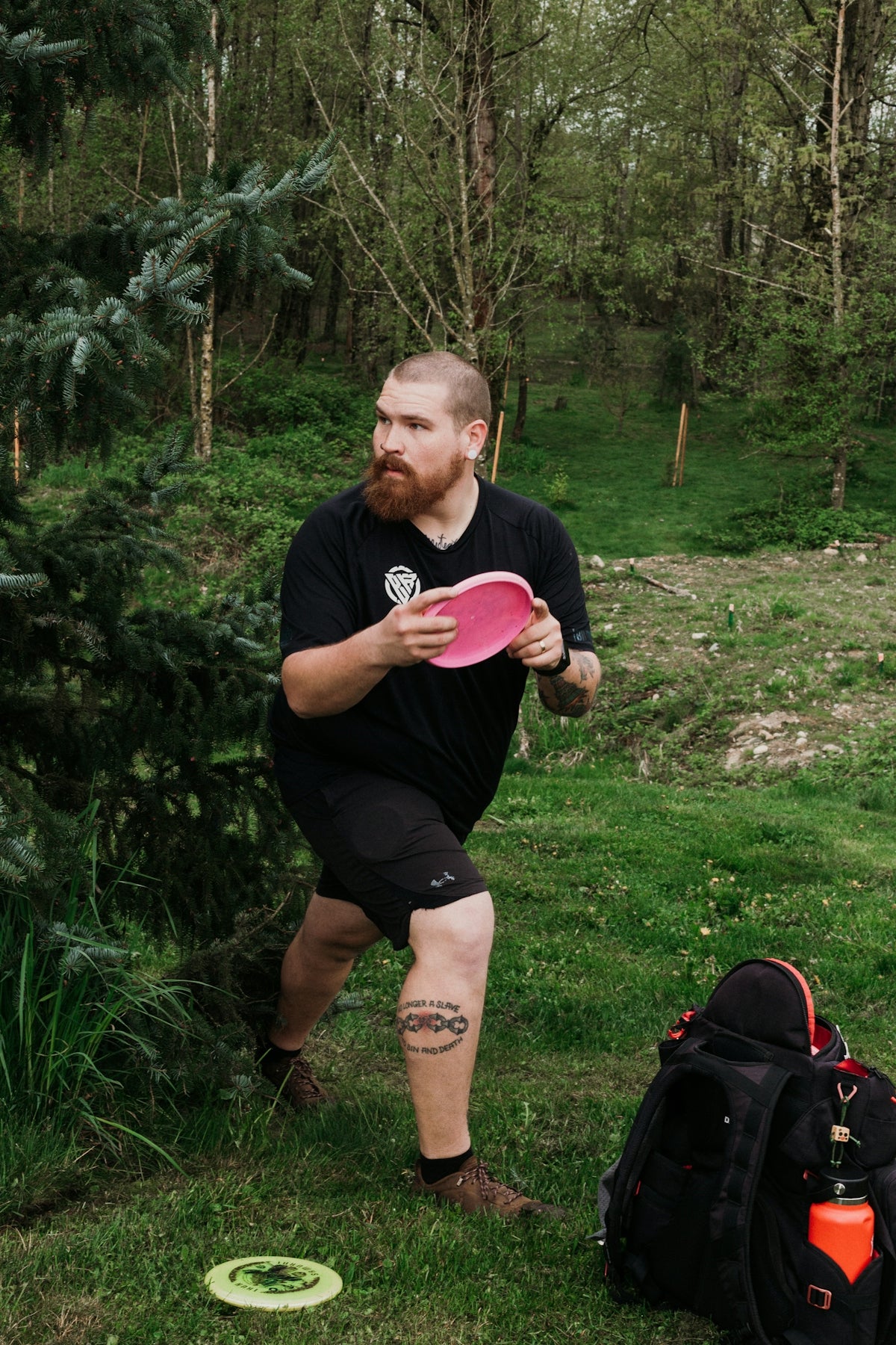 Man throwing a pink disc golf disc in a park.