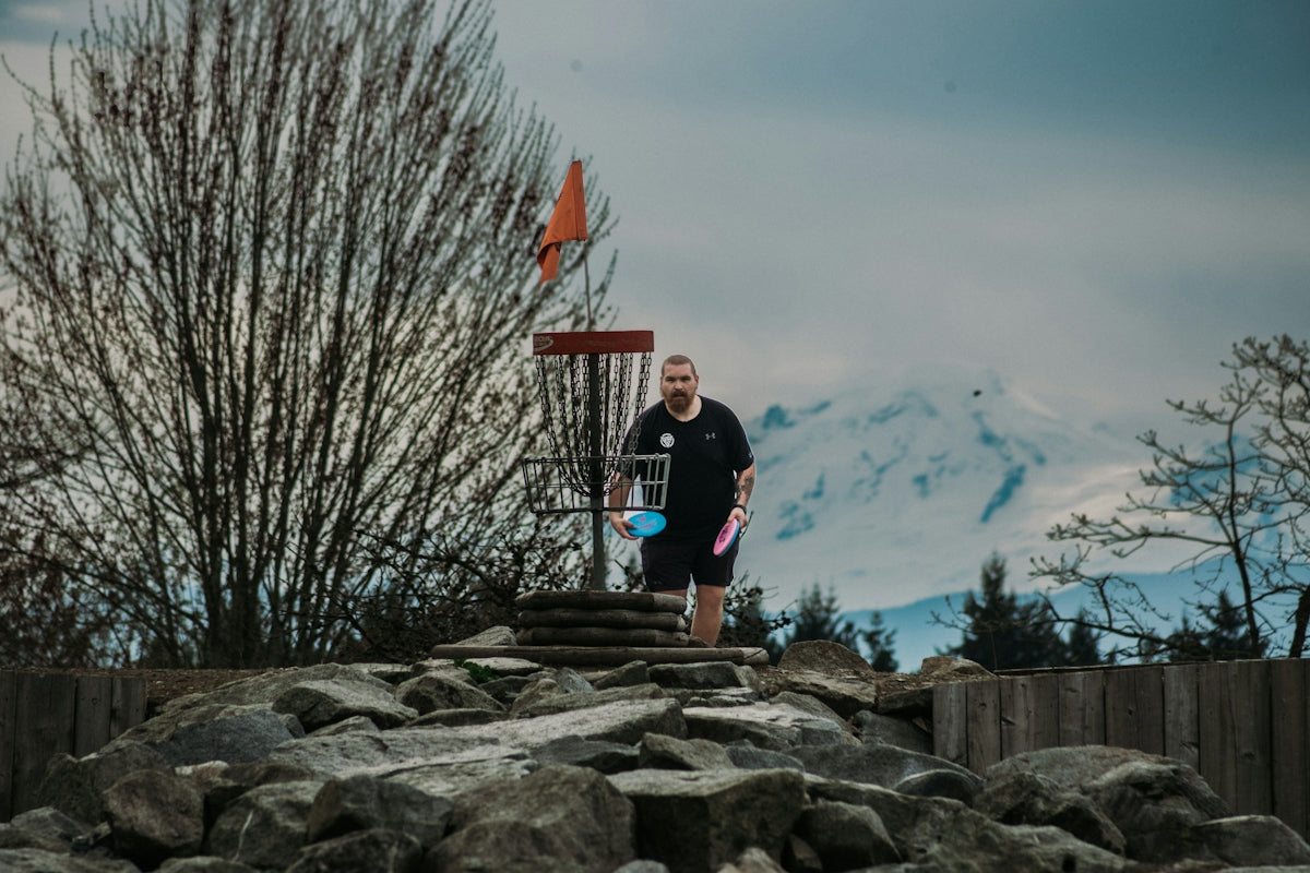 Man playing disc golf with mountains in background